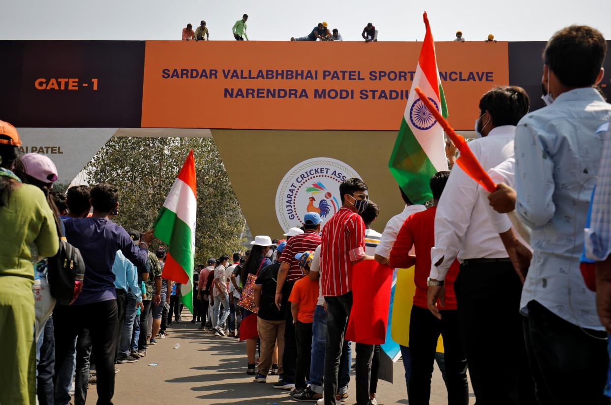 Workers install a hoarding renaming the world’s largest cricket stadium after Narendra Modi, even as fans wait to enter before the start of the third Test match between India and England (REUTERS)