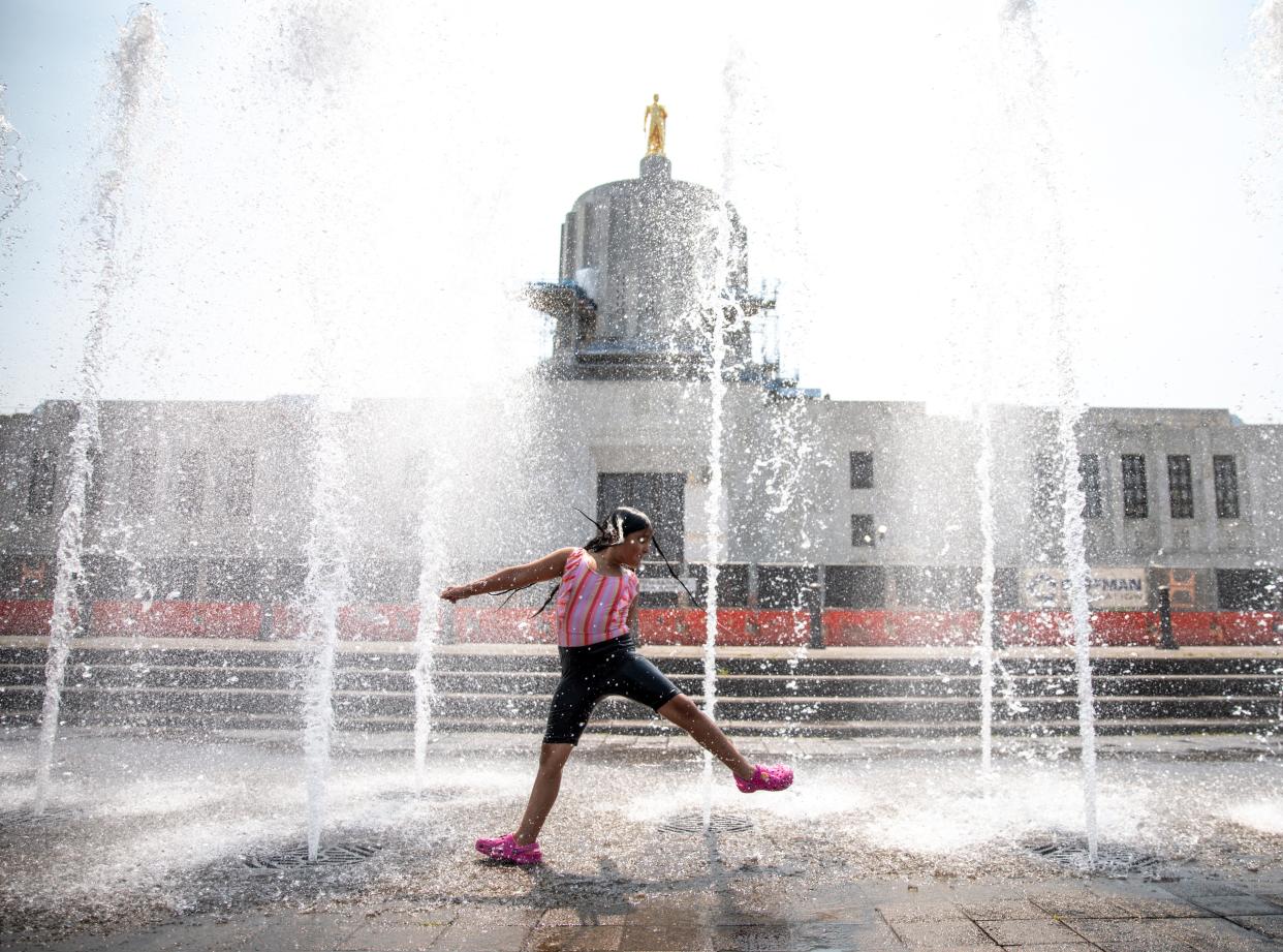 Addilyn Coria cools off with her cousins in the water fountains at the Oregon State Capitol as temperatures surpass 100 degrees on Monday, Aug. 14, 2023 in Salem, Ore. 