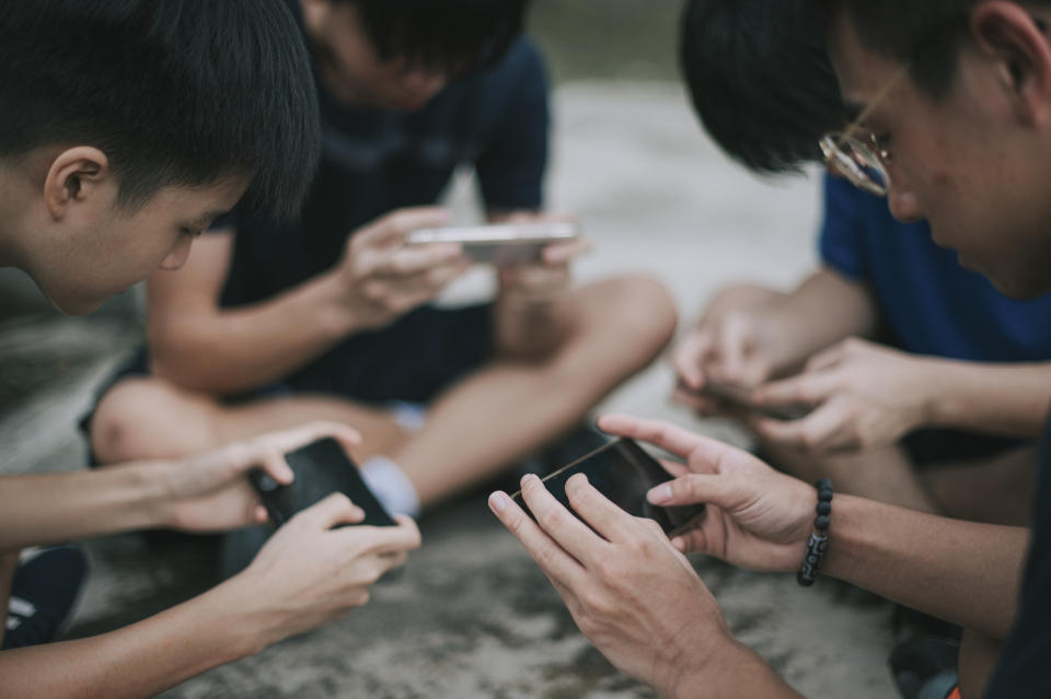 A group of teenage boys playing mobile game.