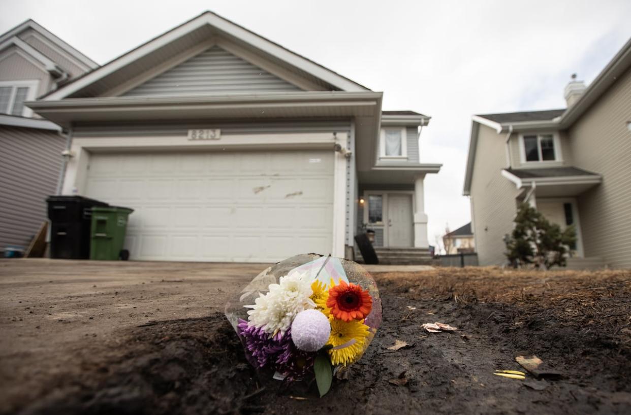 Flowers are placed in front of a house where an 11-year-old boy died after being attacked by two large dogs. (Jason Franson/The Canadian Press - image credit)