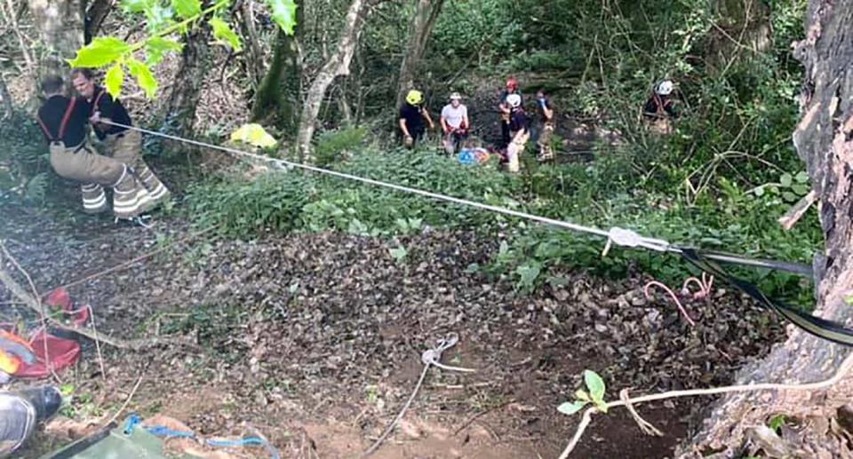 Rescuers assist a woman who had fallen down a ravine.