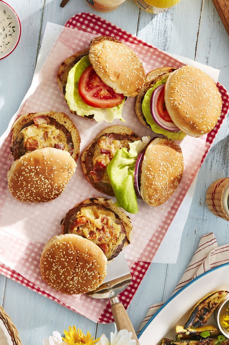 worcestershire glazed burgers on buns with toppings and arranged on a red gingham serving board