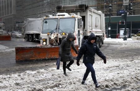 People pass in front of snow plows clearing West 34th street in New York city as the city slowly returned to normal after being hit by winter storm Juno January 27, 2015. REUTERS/Mike Segar