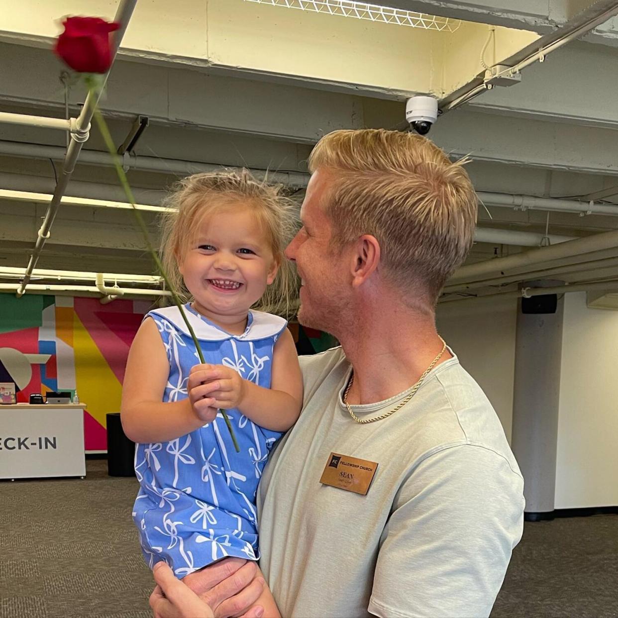 Sean Lowe holding daughter Mia as she holds onto a large rose