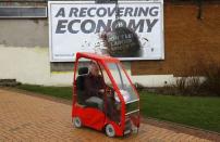 A woman drives a mobility scooter past a Conservative Party billboard in Bedworth, central England, April 1, 2015. At the 2010 general election, Dan Byles won the North Warwickshire seat by just 54 votes, making him the Conservative Member of Parliament with the smallest majority in the country. REUTERS/Darren Staples