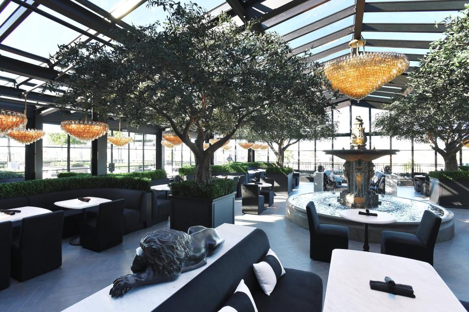 RH Jacksonville, The Gallery at St. Johns Town Center's rooftop restaurant is a skylit garden escape beneath an atrium with retractable glass walls, chandeliers and heritage olive trees. A large fountain serves as the centerpiece of the dining room.