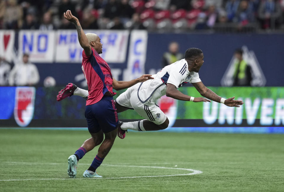 Vancouver Whitecaps' Sergio Cordova, right, is upended by FC Dallas' Nkosi Tafari during the second half of an MLS soccer game in Vancouver, British Columbia, Saturday, March 11, 2023. (Darryl Dyck/The Canadian Press via AP)