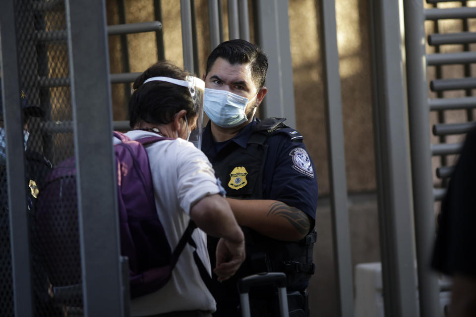 A U.S. Customs and Border Protection officer speaks to people as they cross the border from Mexicali, Mexico, to Calexico, Calif., Wednesday, July 22, 2020, seen from Mexicali. (AP Photo/Gregory Bull)