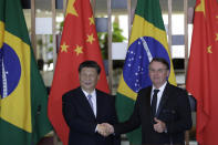 China's President Xi Jinping, left, and Brazil's President Jair Bolsonaro, pose for photos shaking hands at the end of their statements during a bilateral meeting on the sidelines of the 11th edition of the BRICS Summit, at the Itamaraty Palace, in Brasília, Brazil, Wednesday, Nov. 13, 2019. (AP Photo/Eraldo Peres)