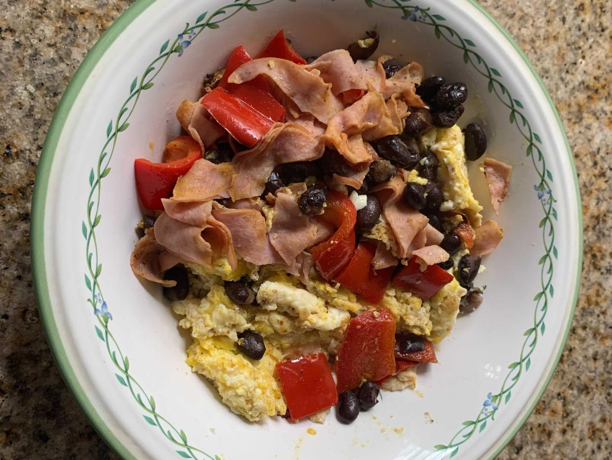 a bowl of scrambled eggs with red peppers, black beans, and turkey.