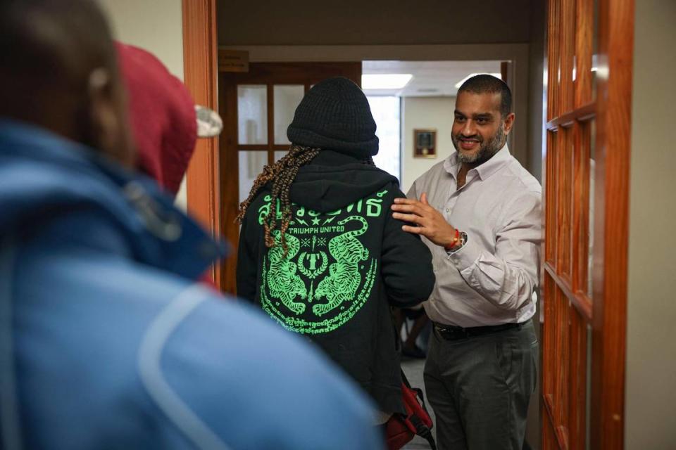 Dámaso Ramírez, a la derecha, da la bienvenida a los migrantes que necesitan asistencia para servicios legales de Catholic Charities el lunes 9 de enero de 2023, en el downtown de Miami.