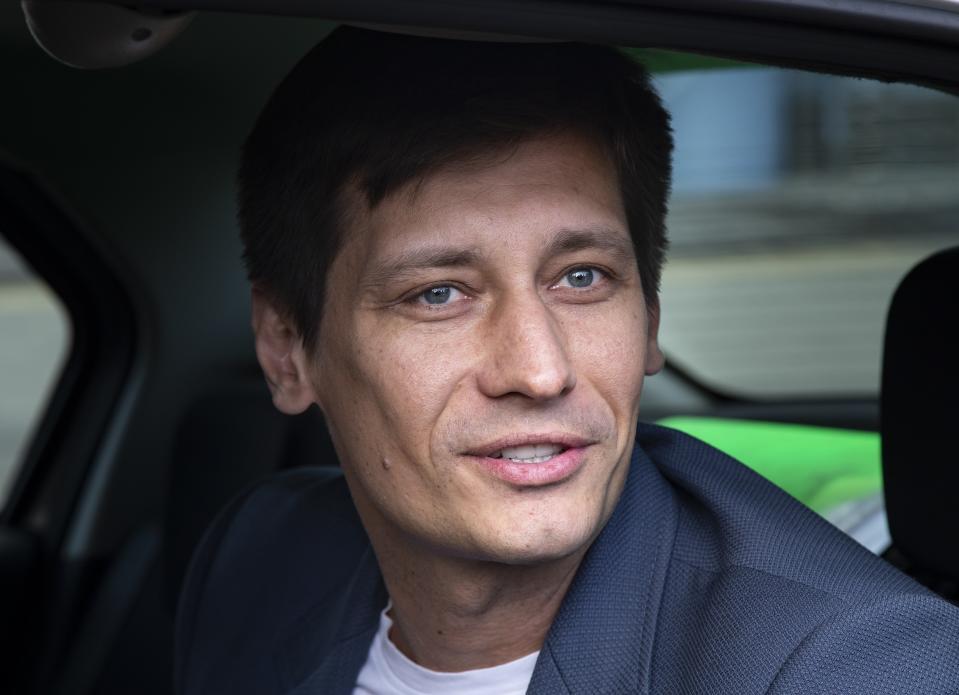 FILE - In this Tuesday, July 30, 2019 file photo, Russian opposition candidate Dmitry Gudkov speaks to journalists sitting inside a police car as he arrives to the court in Moscow, Russia. Russian authorities have ramped up their pressure on dissent ahead of a parliamentary election, arresting one opposition activist and raiding several others' homes. On Tuesday police raided a country home of opposition politician Gudkov, a former lawmaker who has aspired to run for parliament in September. At least two of his associates also had their homes searched. (AP Photo/Alexander Zemlianichenko, File)