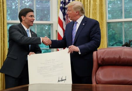 U.S. President Donald Trump shakes hands with Mark Esper after Esper was sworn in as the new Secretary of Defense while they hold a certificate recognizing the appointment in the Oval Office of the White House