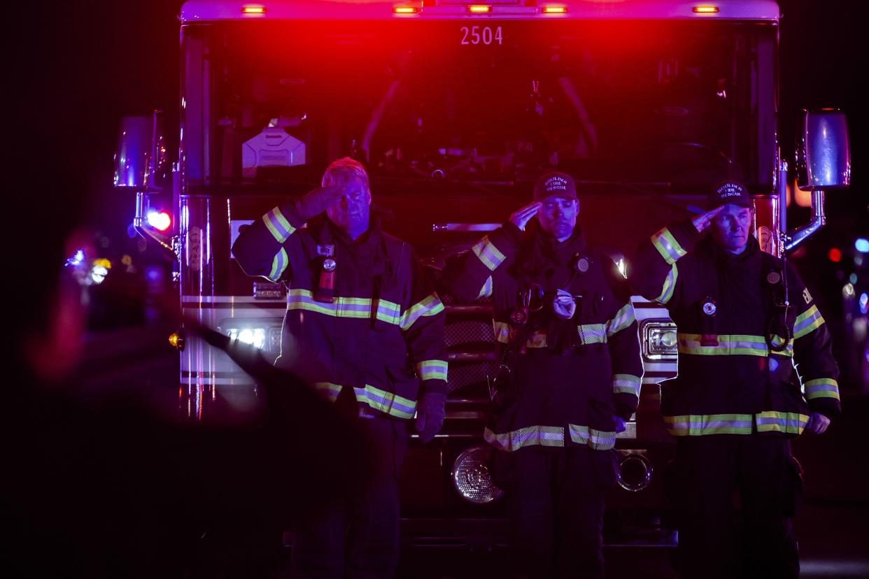 Firefighters salute as a procession carrying the body of a police officer leaves King Sooper's grocery store where a gunman opened fire on March 22, 2021, in Boulder, Colorado.