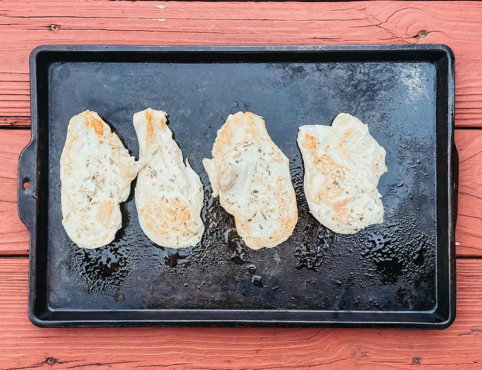 four cooked pieces of chicken on a sheet pan