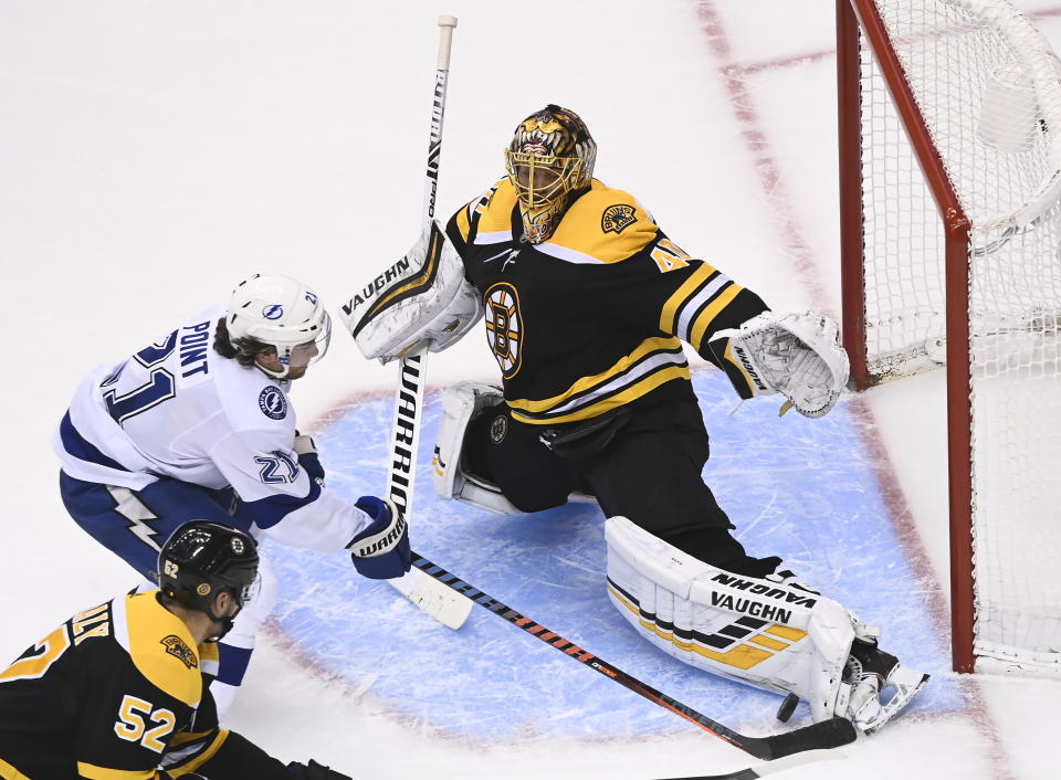 Boston Bruins goaltender Tuukka Rask (40) makes a pad save against Tampa Bay Lightning center Brayden Point (21) as Bruins center Sean Kuraly (52) looks on during the third period of an NHL hockey playoff game Wednesday, Aug. 5, 2020 in Toronto. (Nathan Denette/The Canadian Press via AP)