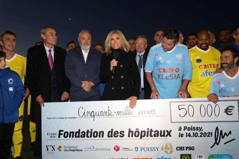 Brigitte Macron, President of the Paris Hospitals Foundation, receives a cheque for 50,000 euros at the end of the charity football match between the Varietes club de France and the carers of the Poissy Saint Germain hospital at the Leo Lagrange stadium in Poissy, France, Oct. 14. - Credit: AP