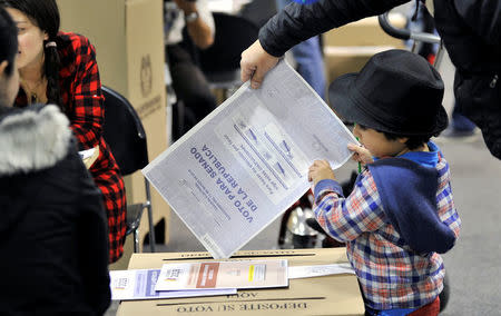 A Colombian casts his vote with the help of his son during the legislative elections in Bogota, Colombia March 11, 2018. REUTERS/Carlos Julio Martinez