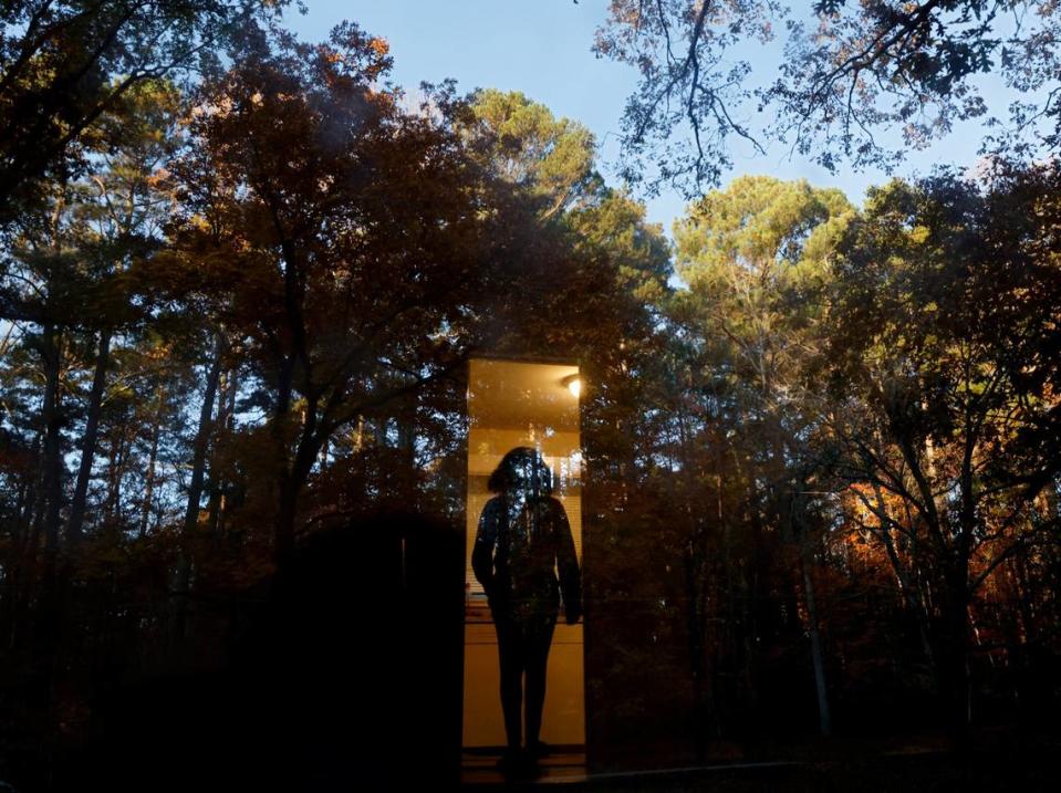 Sheba Everett walks inside as autumn foliage reflects in the front door of her Durham, N.C. home on Thursday, Nov. 3, 2022. Everett, who for two years has rented the house where she lives with her five daughters, received an eviction letter after the Eno River Association planned to transfer the land to the state park system.