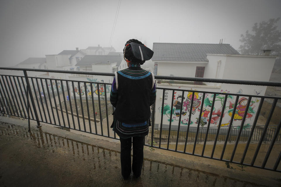 A Yi woman watches new village houses decorated with colourful paintings which were built by the Chinese government for the ethnic minority members in Ganluo county, southwest China's Sichuan province on Sept. 10, 2020. China's ruling Communist Party says its initiatives have helped to lift millions of people out of poverty. Yi ethnic minority members were moved out of their mountain villages in China’s southwest and into the newly built town in an anti-poverty initiative. (AP Photo/Andy Wong)