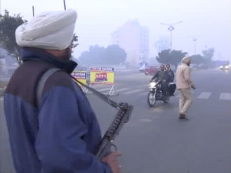 A policeman stands guard with a gun as vehicles pass by, following what officials said was an attack on an Indian Air Force base in Pathankot on Saturday, near the border with Pakistan, in Ludhiana, Punjab state, India, in this still frame taken from video, January 2, 2016. REUTERS/ANI/via Reuters TV