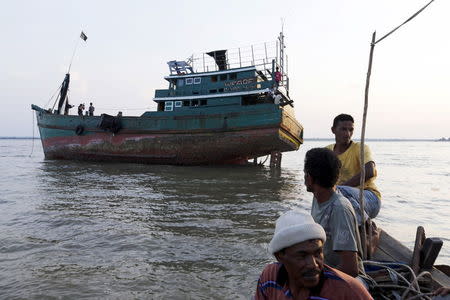 Acehnese fishermen pass near an abandoned boat which carried Rohingya and Bangladeshi migrants from Thailand, found off the coast near the city of Kuta Binje, Indonesia's Aceh Province May 20, 2015. REUTERS/Beawiharta