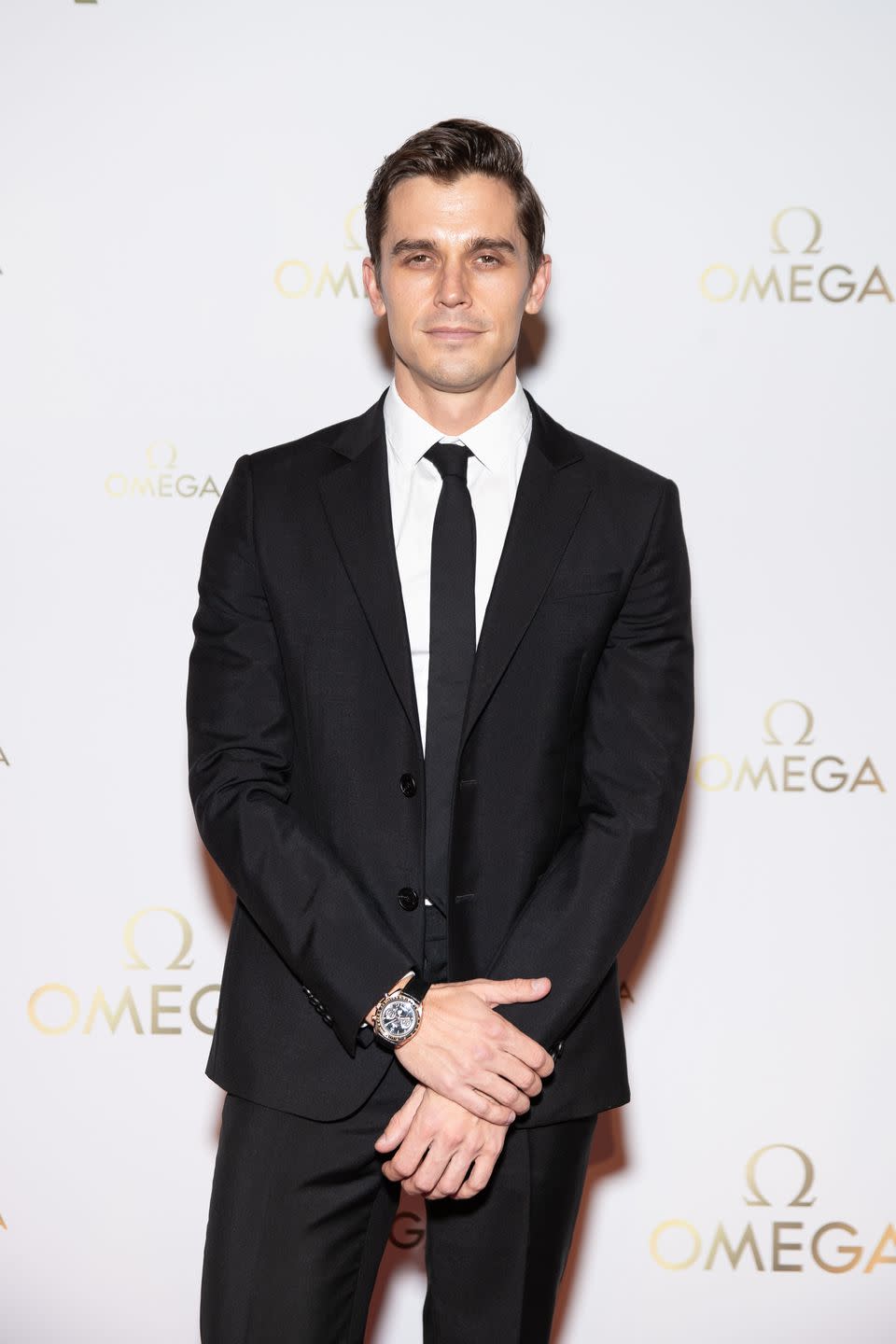 antoni porowski with a stern facial expression, wearing a black suit