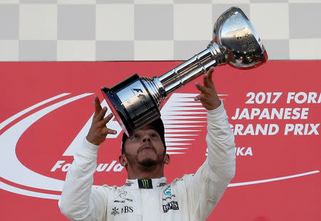 Kimi Raikkonen raises his winner's trophy on the podium as Felipe