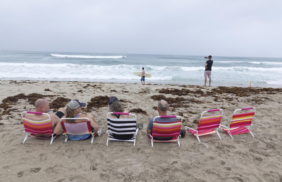 Spectators watch surfers in Delray Beach, Sunday, Aug. 2, 2020, as Tropical Storm Isaias brushes past the East Coast of Florida. (Joe Cavaretta/South Florida Sun-Sentinel via AP)