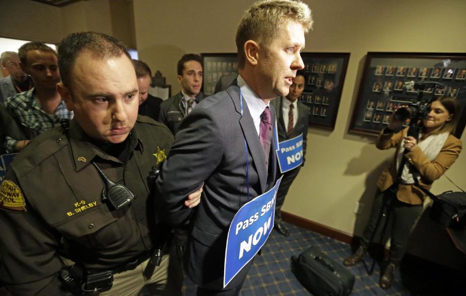 A Utah Highway Patrol trooper arrests a protester who blocked the doors to the higher education committee hearings Monday, Feb. 10, 2014, at the Utah State Capitol, in Salt Lake City. The protesters called for a statewide anti-discrimination law that protects sexual or gender orientation. (AP Photo/Rick Bowmer)