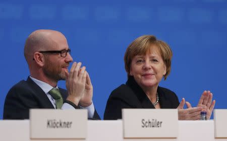 Germany's Christian Democratic Union (CDU) secretary general Peter Tauber and German Chancellor and leader of the CDU Angela Merkel applaud after a vote on a resolution about refugees at the CDU party congress in Karlsruhe, Germany December 14, 2015. REUTERS/Ralph Orlowski