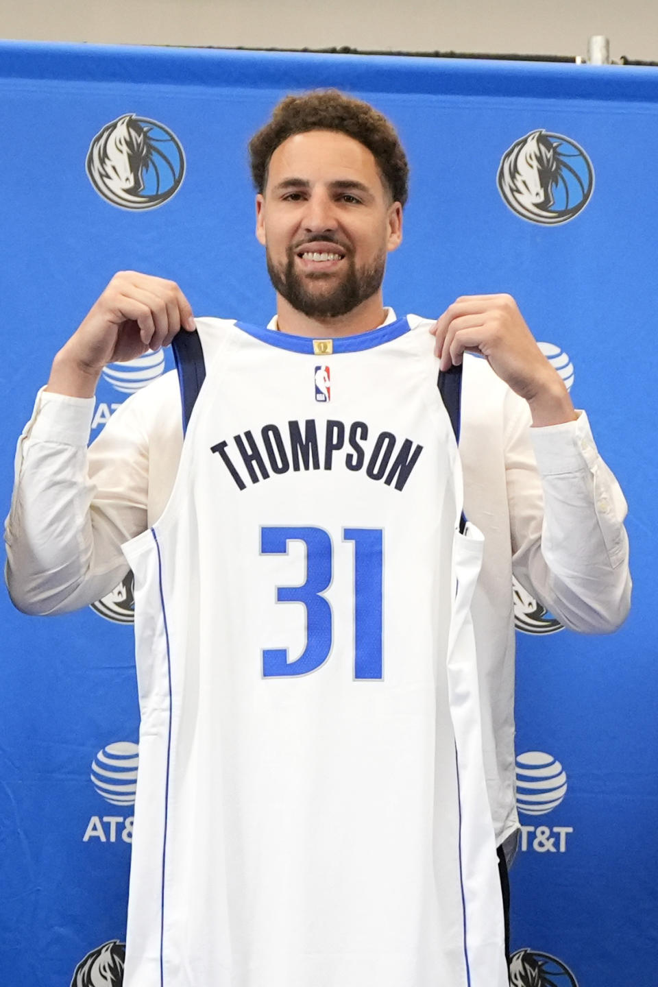 Klay Thompson poses with his jersey after an NBA news conference at the Dallas Mavericks basketball team's practice facility in Dallas, Tuesday, July 9, 2024.(AP Photo/Tony Gutierrez)