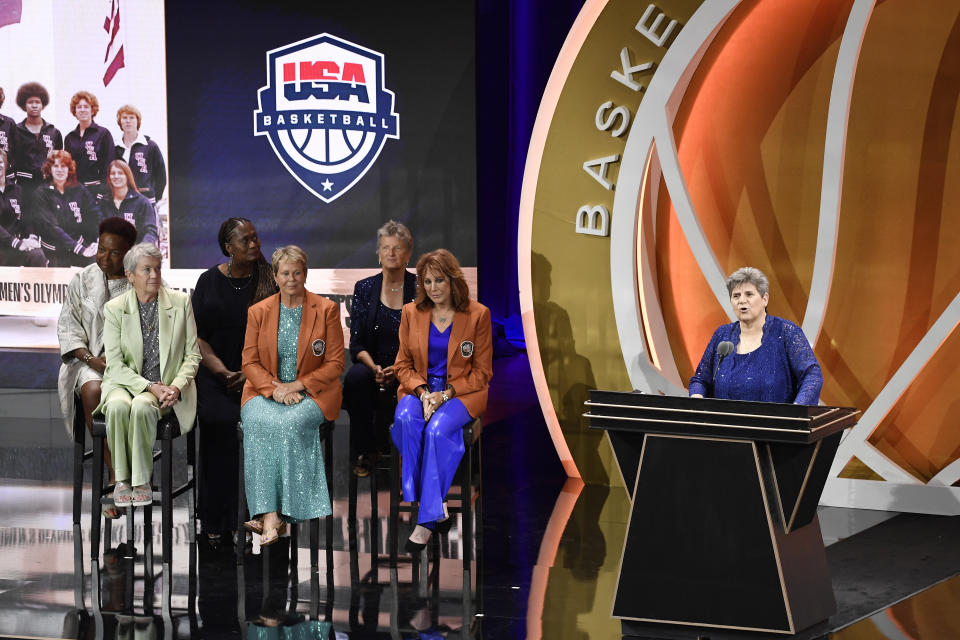 Juliene Brazinski Simpson speaks on behalf of the 1976 U.S. women's Olympic team as players listen during their enshrinement at the Basketball Hall of Fame, Saturday, Aug. 12, 2023, in Springfield, Mass. (AP Photo/Jessica Hill)