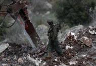 In this Thursday, Dec. 13, 2018 photo, an Israeli soldier walks next to an excavator, near the southern border village of Mays al-Jabal, Lebanon, Thursday, Dec. 13, 2018. As Israeli excavators dig into the rocky ground, Lebanese across the frontier gather to watch what Israel calls the Northern Shield operation aimed at destroying attack tunnels built by Hezbollah. But Lebanese soldiers in new camouflaged posts, behind sandbags, or inside abandoned homes underscore the real anxiety that any misstep could lead to a conflagration between the two enemy states that no one seems to want. (AP Photo/Hussein Malla)