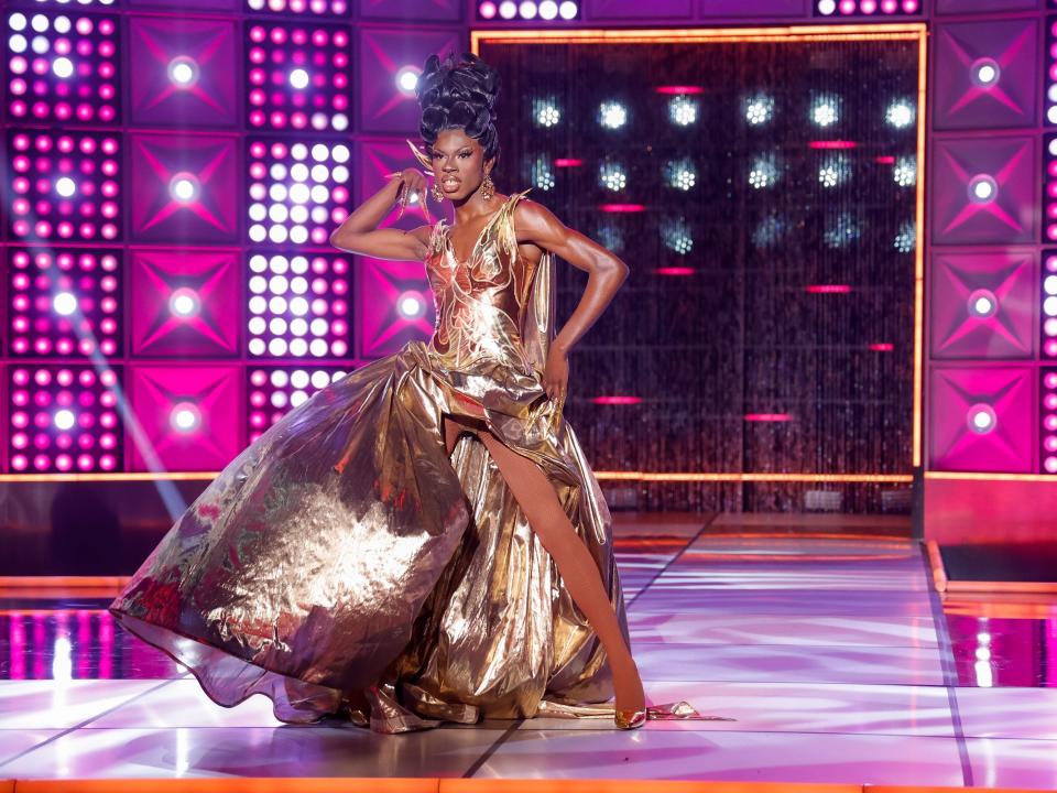 Luxx Noir London poses on the runway in a gold gown and heels in this still from episode 3 of "RuPaul's Drag Race" season 15.