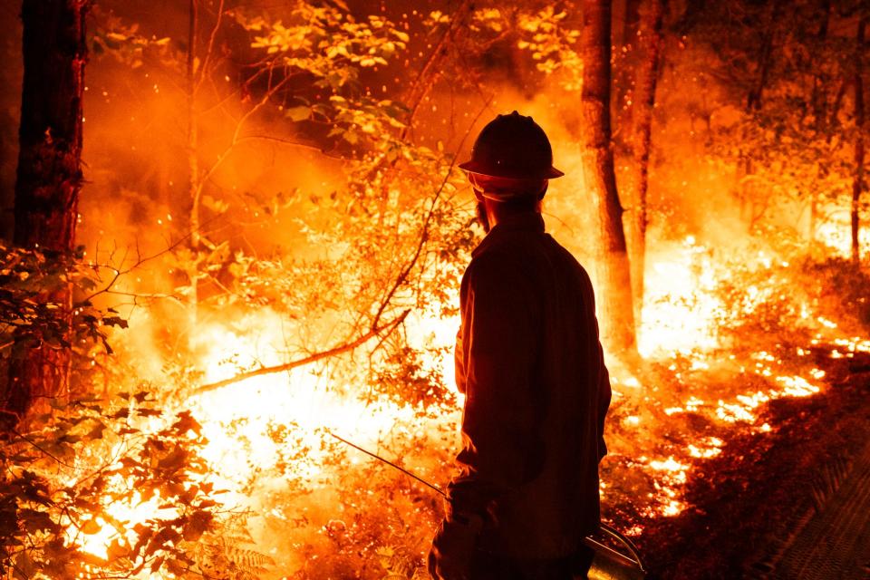 A New Jersey Forest Fire Service firefighter is silhouetted by a fully involved section of a 200-acre wildfire early on Monday, Aug. 21, 2023, in Wharton State Forest along Jackson Road within Waterford Township. No reports of injuries or threats to buildings  since the fire was spotted Sunday night.