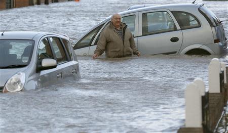 A man stands up to his waist in flood water in a residential street in Rhyl, north Wales December 5, 2013. REUTERS/Phil Noble