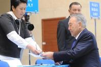 Kazakh President Nursultan Nazarbayev (R) prepares to cast his ballot at a polling station in Astana on April 26, 2015
