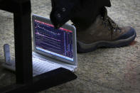 An investor places his computer showing shares index under his seat at a brokerage house in Beijing, Tuesday, Jan. 22, 2019. Asian markets were mostly lower on Tuesday after the International Monetary Fund trimmed its global outlook for 2019 and 2020. This came after China said its economy grew at the slowest pace in 30 years. (AP Photo/Andy Wong)