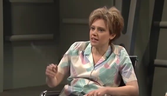 Kate McKinnon sitting down as Ms. Rafferty in "Saturday Night Live"