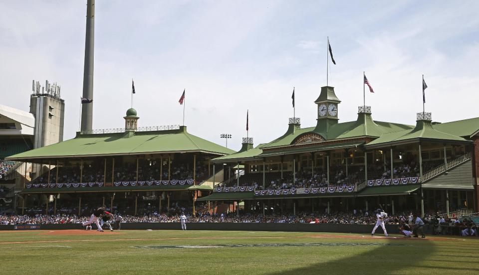 The Arizona Diamondbacks' Trevor Cahill, left, throws the first pitch during the second game of the two-game Major League Baseball opening series between the Los Angeles Dodgers and the Arizona Diamondbacks at the Sydney Cricket Ground in Sydney, Sunday, March 23, 2014. (AP Photo/Rick Rycroft)