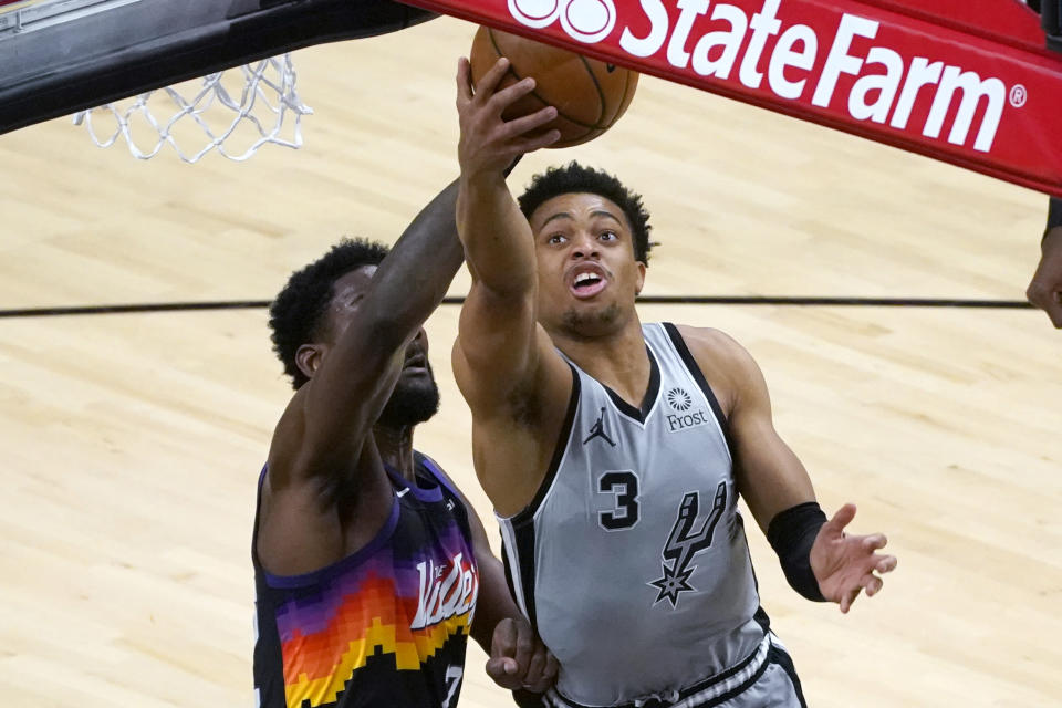 San Antonio Spurs forward Keldon Johnson (3) drives past Phoenix Suns center Deandre Ayton during the first half of an NBA basketball game Saturday, April 17, 2021, in Phoenix. (AP Photo/Rick Scuteri)