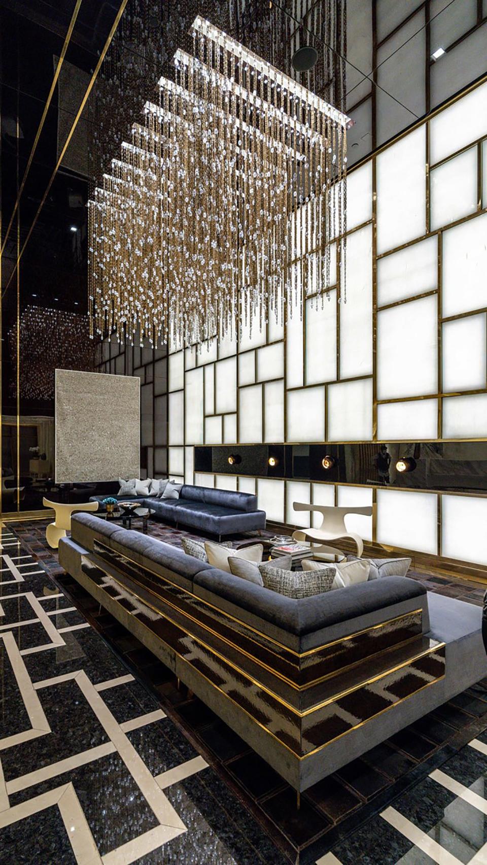 a light fixture hanging over a blue couch and geometric patterned floor in the lobby of luxury skyscraper Central Park Tower