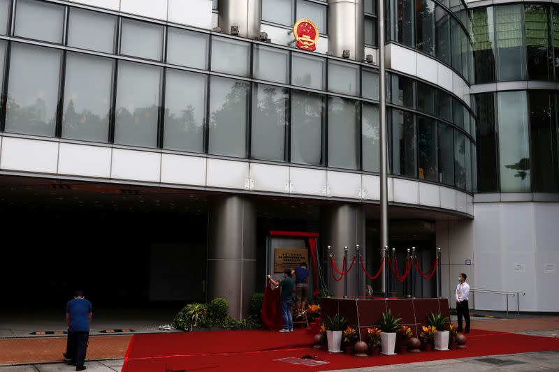 Workers work on a board after the opening of temporary national security office, in Hong Kong