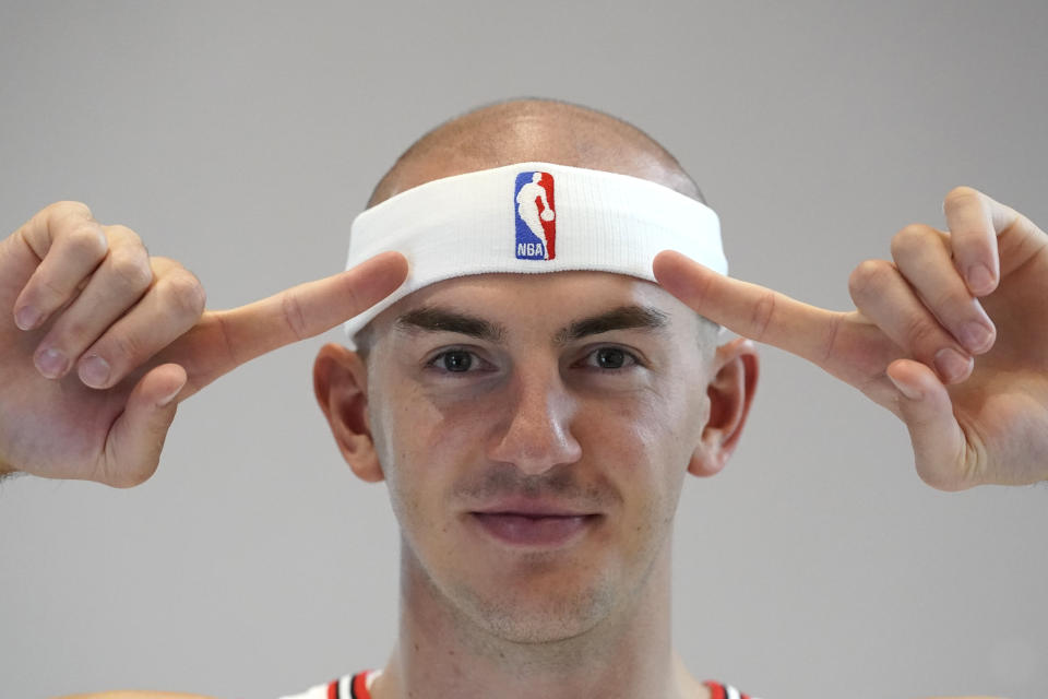 Chicago Bulls' Alex Caruso points to his trademark headband during the Bulls NBA basketball media day Monday, Sept. 26, 2022, in Chicago. (AP Photo/Charles Rex Arbogast)