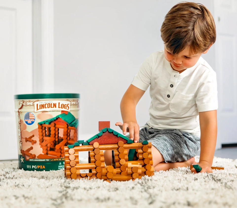 Child playing with tin of Lincoln Log toys