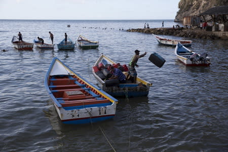 Men unload containers from a boat in the bay of Rio Caribe a town near caribbean islands, in the eastern state of Sucre, Venezuela October 29, 2015. REUTERS/Carlos Garcia Rawlins