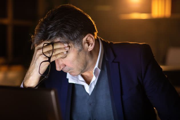 Tired businessman with eyes closed, feeling headache, trying to stay concentrated for late night work at office (Photo: miodrag ignjatovic via Getty Images)