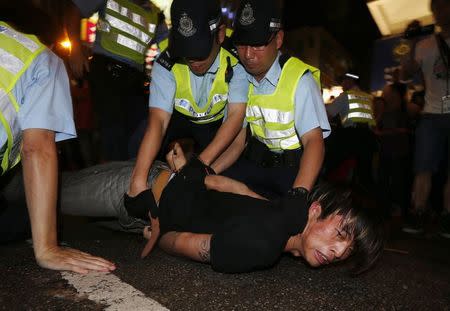 An anti-Occupy Central protester is restrained by policemen after he broke through a cordon line, trying to charge pro-democracy protesters, at Hong Kong's shopping Mongkok district, where a main road is occupied, October 3, 2014. REUTERS/Bobby Yip