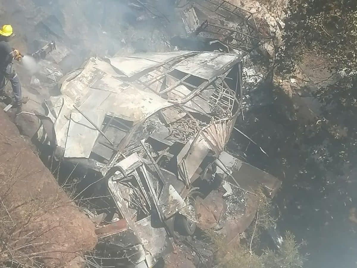 Firefighters hose down a bus after it crashed off the R518, killing a few dozen, in Waterberg District, Limpopo Province, South Africa (via REUTERS)